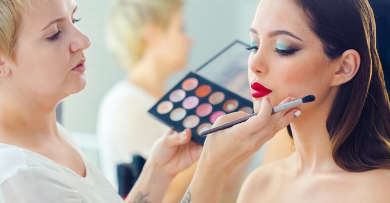 make up artist doing professional make up of young woman