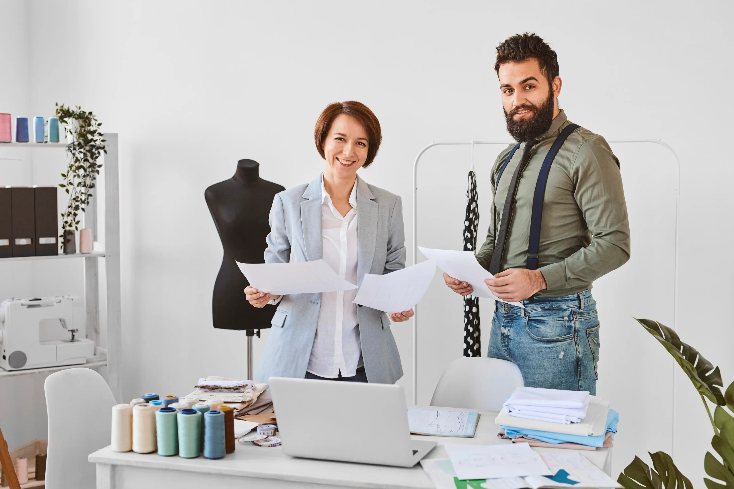 two fashion designers posing atelier with clothing line plans